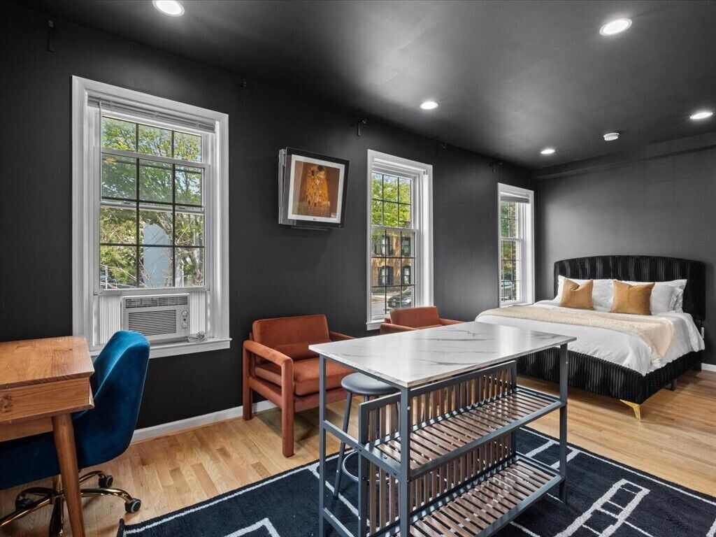 A modern bedroom with a bed, a desk, and two chairs.