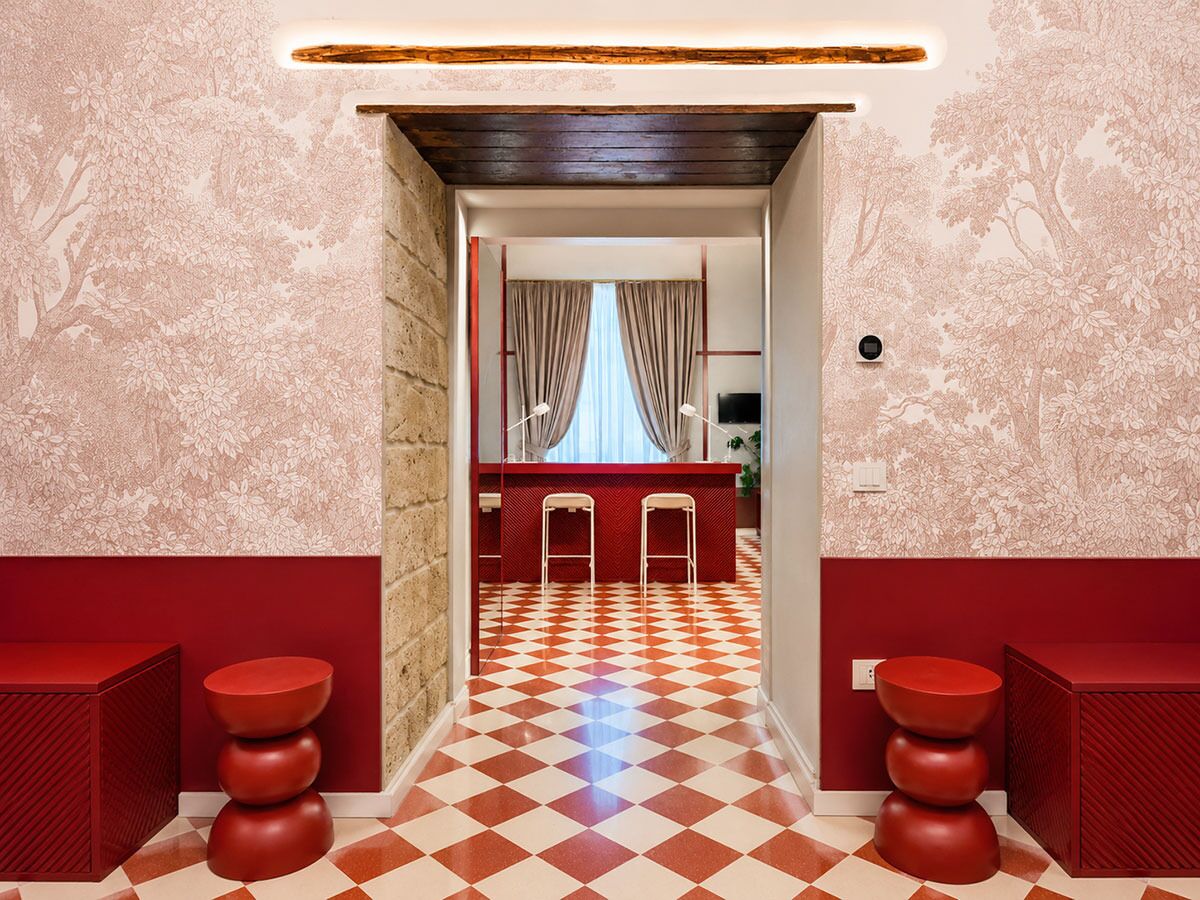 Un couloir au sol à carreaux menant à un espace bar équipé de tabourets et d’un comptoir.