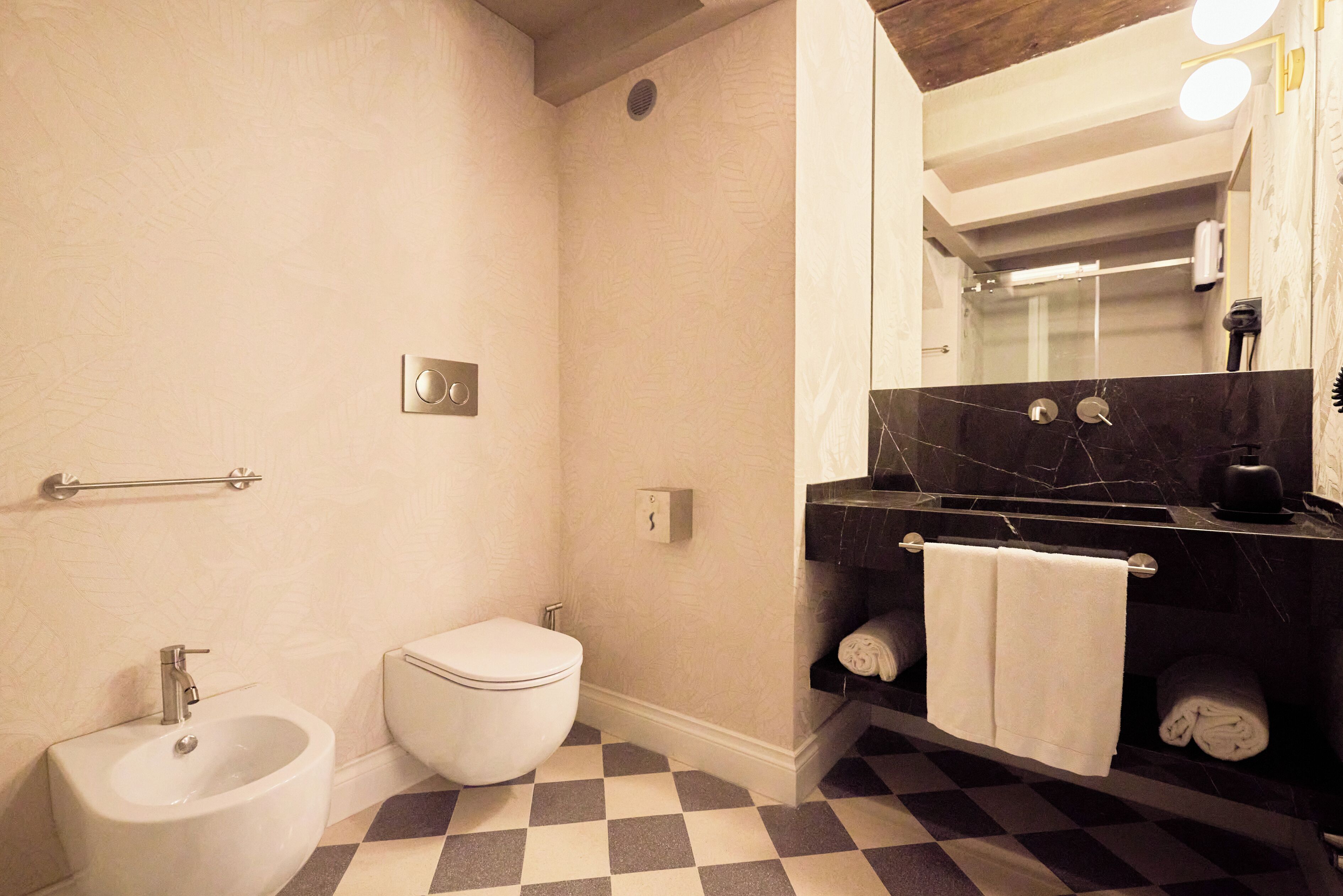 Une salle de bain équipée d’un bidet, de toilettes et d’un lavabo avec un porte-serviettes.