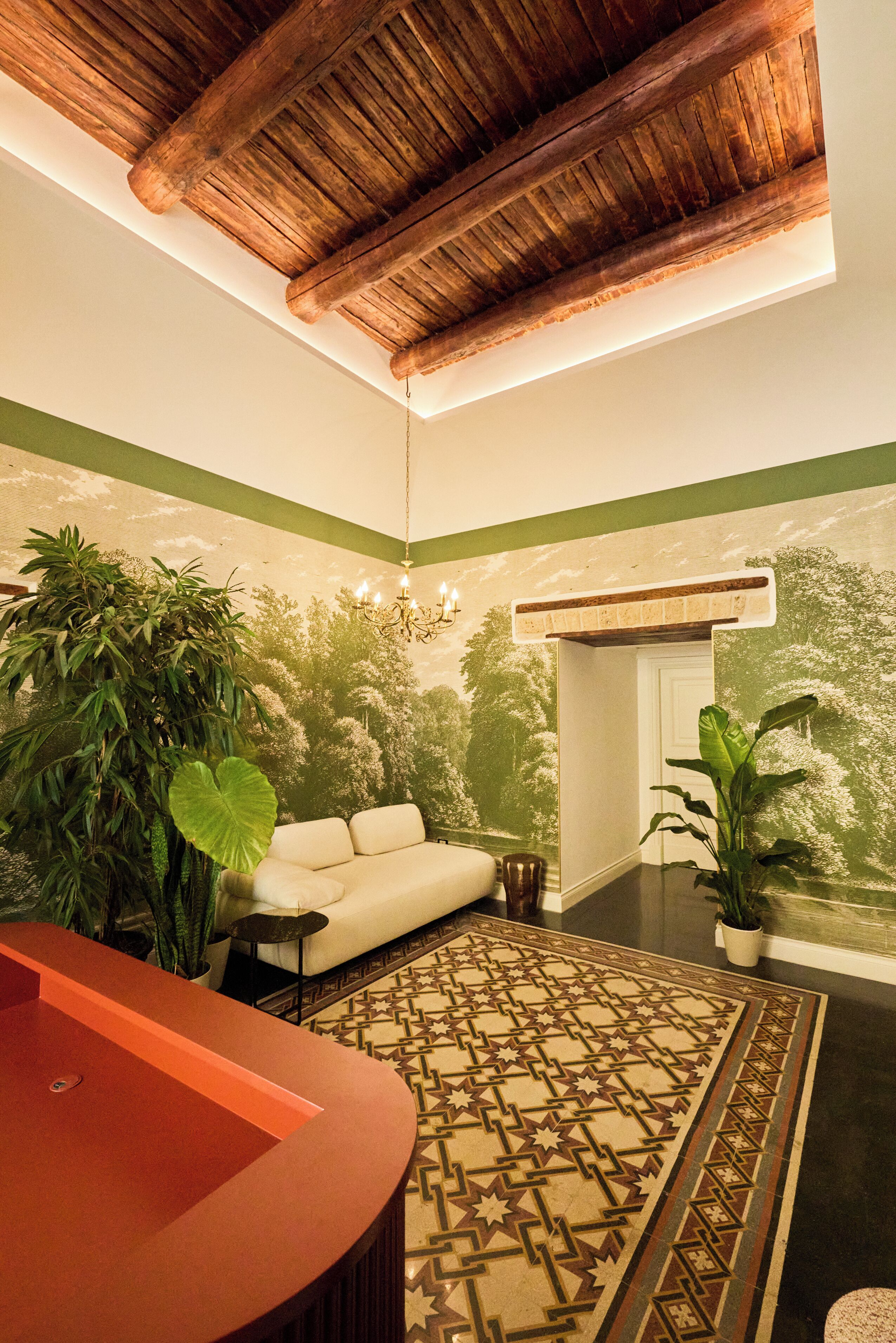 A room with a wooden ceiling, a sofa, a patterned rug, and a reception desk.
