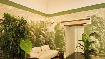 A room with a wooden ceiling, a sofa, a patterned rug, and a reception desk.