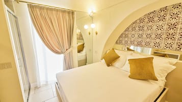 Quarto de hotel com uma cama, cortinas, chuveiro e uma parede com padrão decorativo.