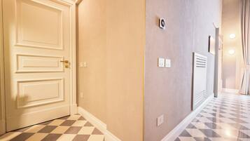 A hallway with a checkered floor, a white door, and a wall with a thermostat and light switch.