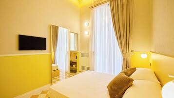 A hotel room with a bed, a mirror, a bathroom, and a checkered floor.