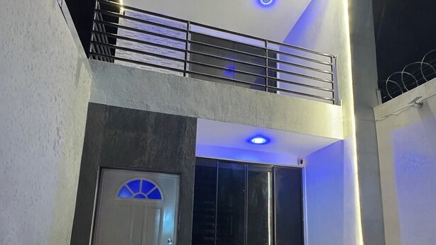 A two-story building with a balcony, a door with a glass panel, and a tiled floor.