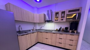 A modern kitchen with wooden cabinets, a stainless steel refrigerator, and a built-in oven.