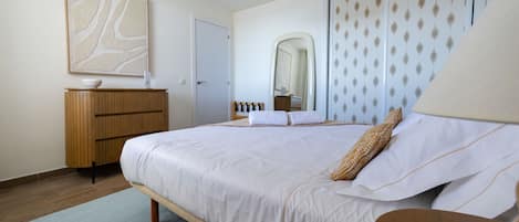 Ein Schlafzimmer mit einem Bett, einer hölzernen Kommode und einem großen Spiegel.