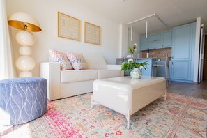 A modern living room with a sofa, ottoman, and a colorful rug. - Sun & Figs (San Bartolomé de Tirajana)