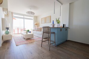 A modern living room with a sofa, coffee table, and a dining area with chairs.