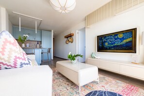 A modern living room with a white sofa, a colorful rug, a coffee table with a plant, and a large painting on the wall. - Sun & Figs (San Bartolomé de Tirajana)