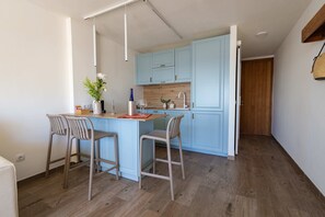 A compact kitchen with light blue cabinets, a wooden countertop, and two bar stools.