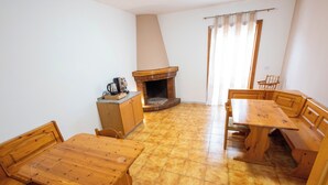 Ein Zimmer mit Holztisch, Stühlen, Kamin und einer Kaffeemaschine.