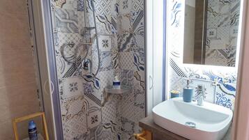 A bathroom with a shower, a sink, and a mirror.