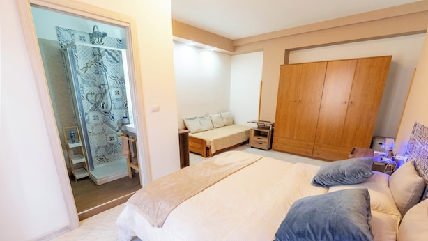 Ein Schlafzimmer mit Bett, Nachttischen, einem Kleiderschrank und einem Badezimmer mit Dusche.