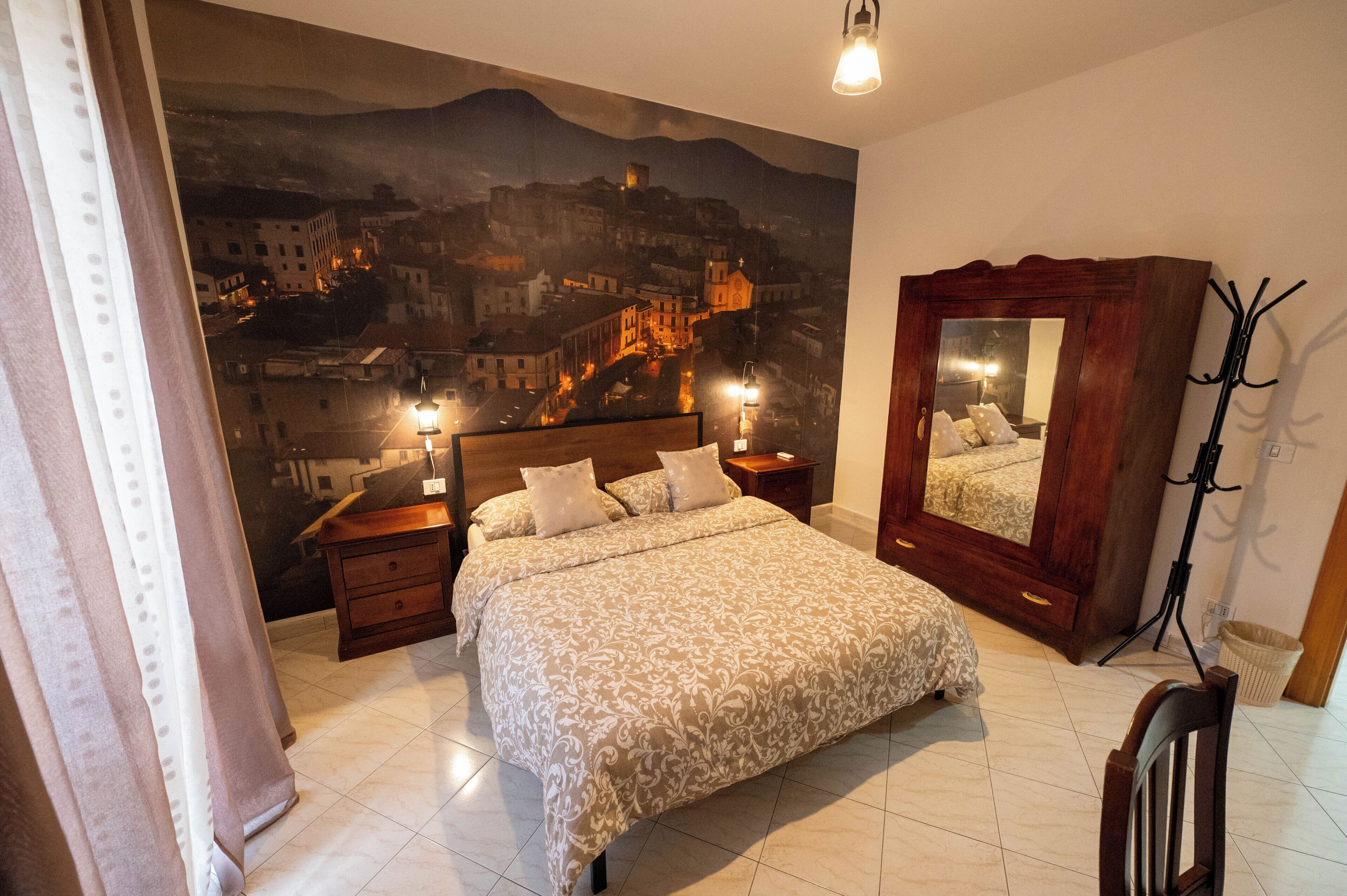 Ein Schlafzimmer mit einem Bett, zwei Nachttischen, einem Spiegel und einer Lampe.
