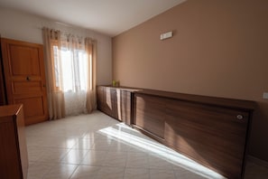 A room with a wooden door, a cabinet, and a window with curtains.
