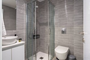 A modern bathroom with a glass-enclosed shower, a white sink, and a toilet. - Opal Signature Studio (Larnaca)