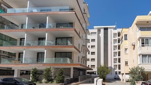 Um edifício residencial de vários andares com varandas, uma garagem visível e um céu claro.