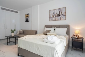 Ein Hotelzimmer mit einem Bett, einem Sofa, einem Nachttisch mit Lampe und einem Wandbild.