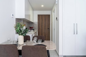 Eine moderne Küche mit Essbereich, ausgestattet mit einer Marmorarbeitsplatte, einer Holztür und einem weißen Schrank mit Griff.