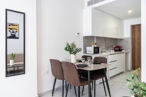 A modern kitchen with white cabinets, a microwave, and a coffee machine. - Opal Signature Studio (Larnaca)