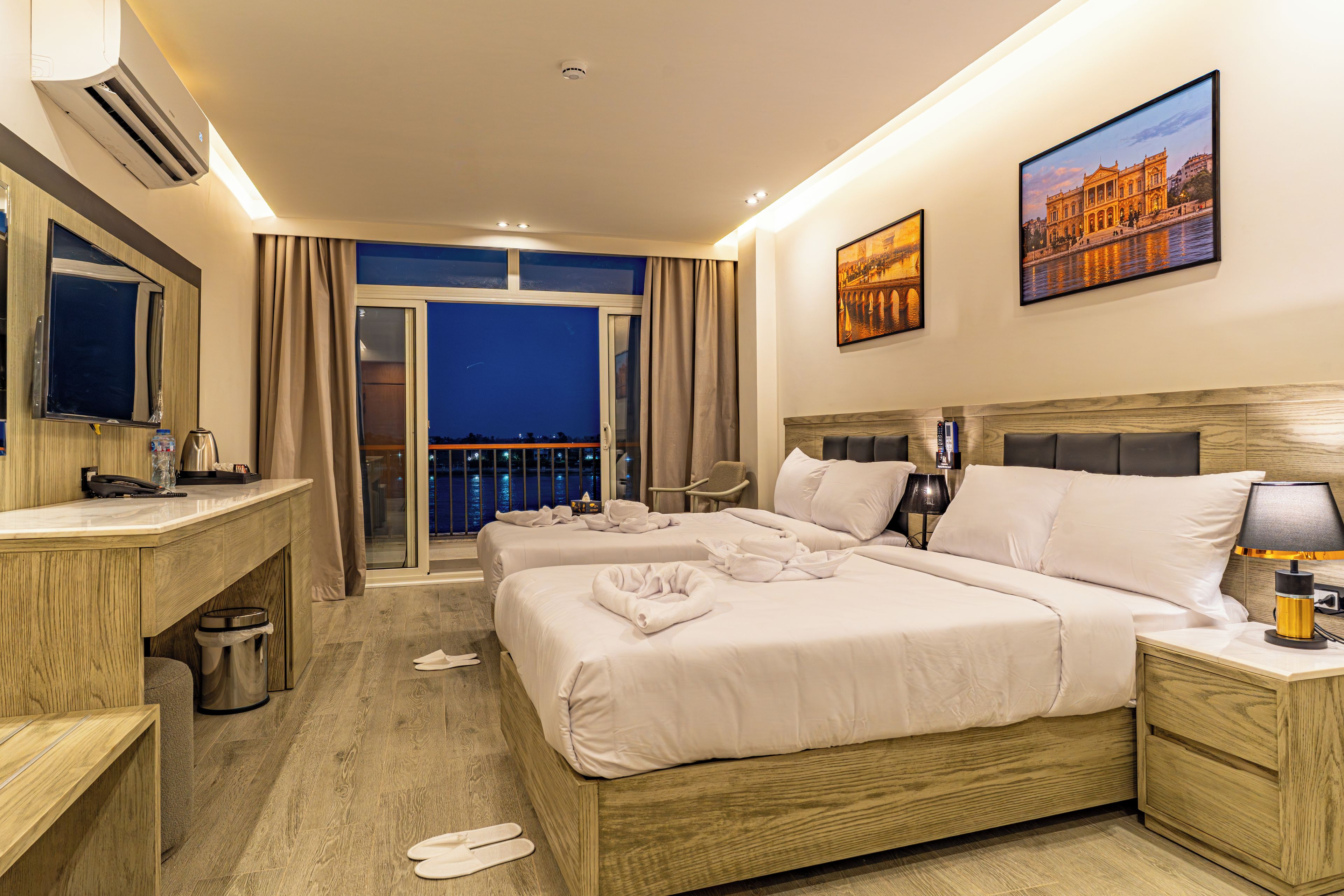 A hotel room with a balcony, a bed, a desk, and a bathroom.