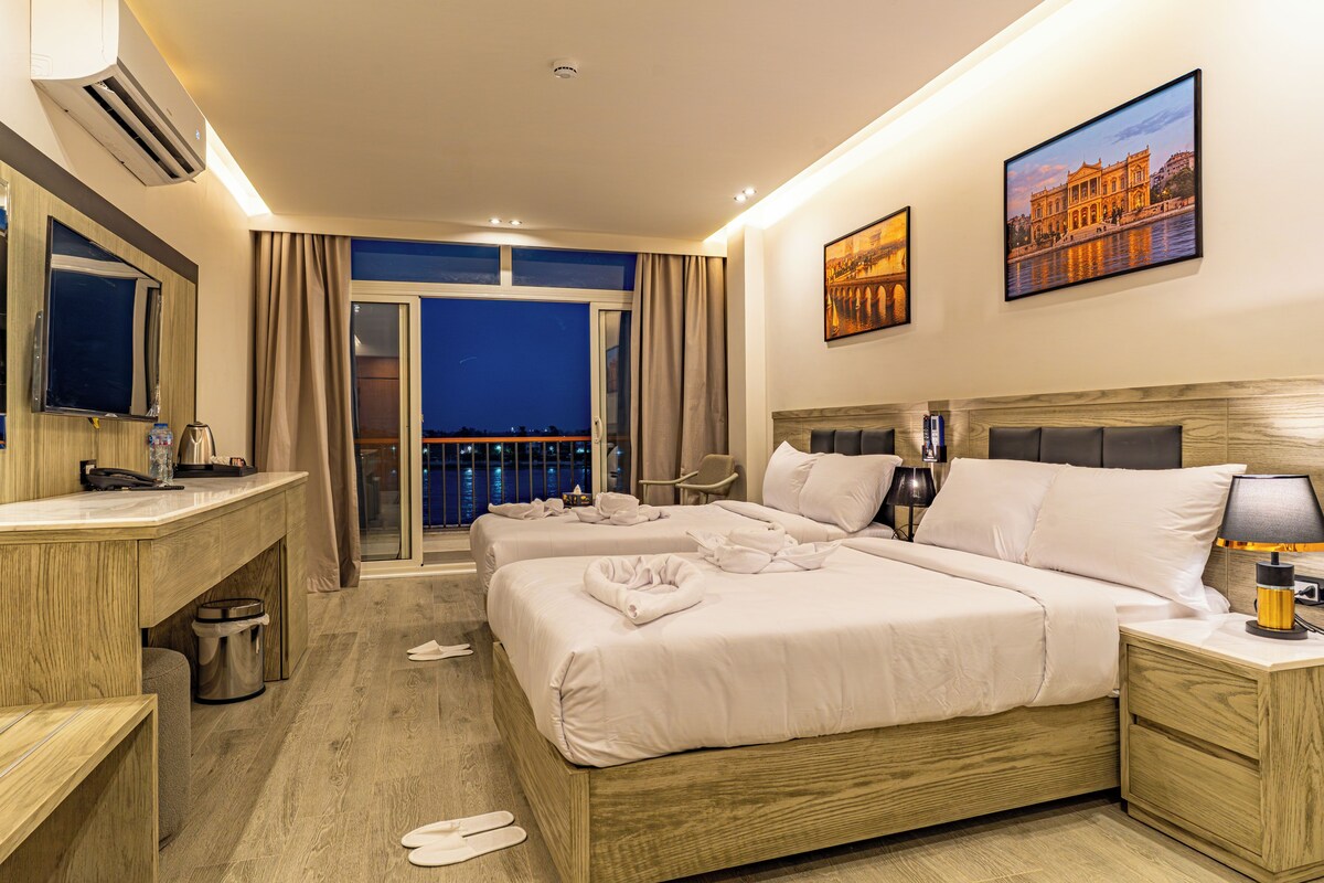 A hotel room with a balcony, a bed, a desk, and a bathroom.