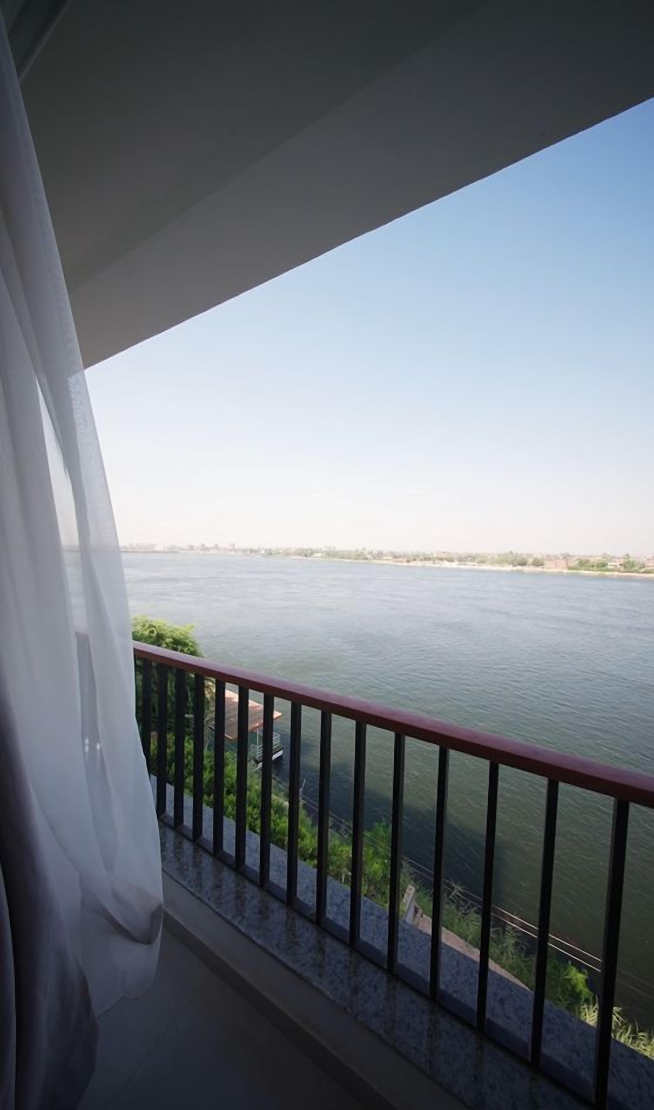 Un balcon avec vue sur une rivière et sur le paysage urbain au loin.