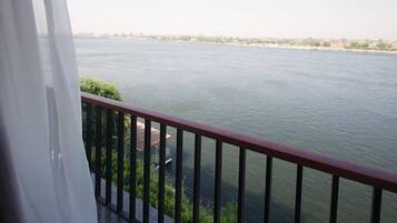 Un balcon avec vue sur une rivière et sur le paysage urbain au loin.