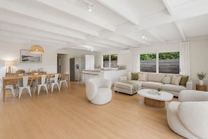 A spacious living area with a dining table, sofas, and a kitchen in the background. - Moonbay by Ready Set Stay (Rye)