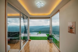 A modern interior with a large sliding glass door leading to a balcony with a mountain view.