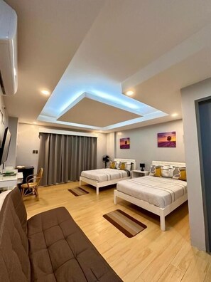 Una habitación de hotel moderna con dos camas, un sofá, un escritorio y una lámpara en el techo.