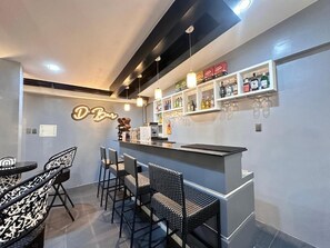 A bar area with a counter, bar stools, and shelves with bottles and glasses.