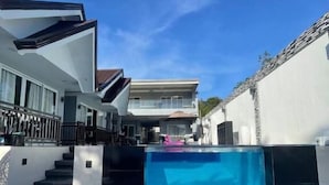 Una propiedad residencial moderna con piscina, una escalera que lleva al segundo piso y una entrada con portón.