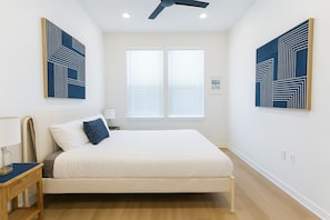 A bedroom with a bed, a nightstand, a lamp, and two windows with blinds. - Stunning 1BR Getaway I Washer-Dryer&Pool (Sherman)