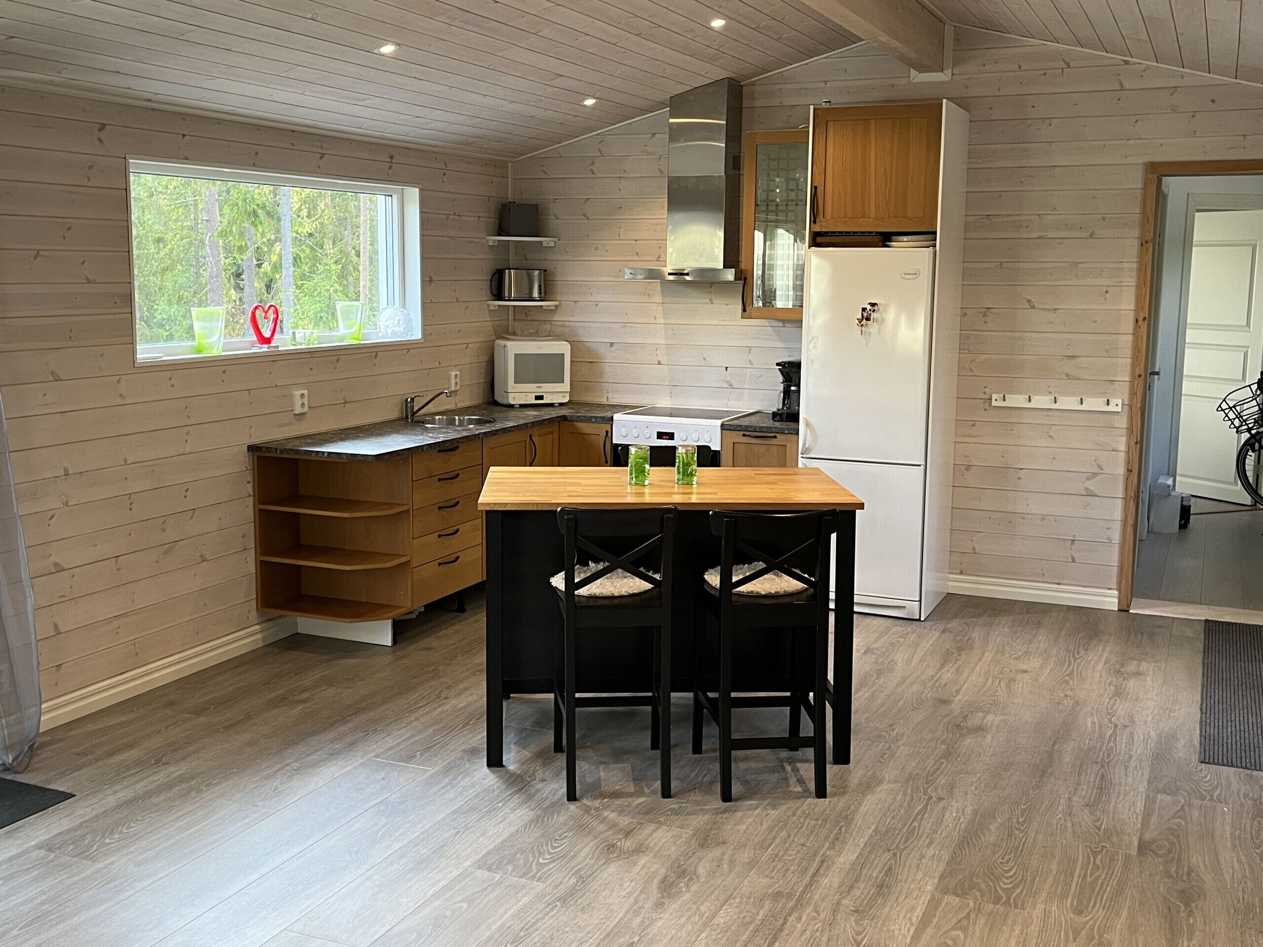 A compact kitchen with wooden cabinetry, a built-in microwave, and a refrigerator.