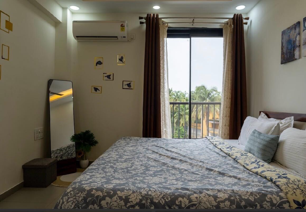 Ein Schlafzimmer mit Bett, Spiegel und einem Balkon mit Vorhängen.