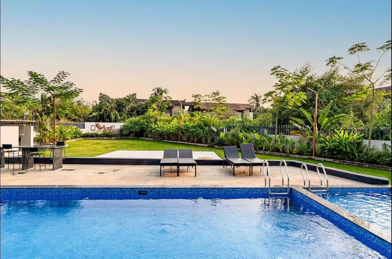 Una piscina con sillones de descanso y un césped cuidado.