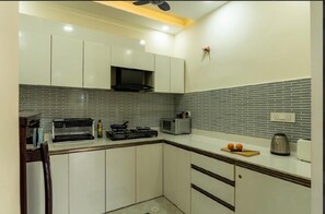 Una cocina con armarios blancos, microondas, hervidor y tostadora sobre la encimera.