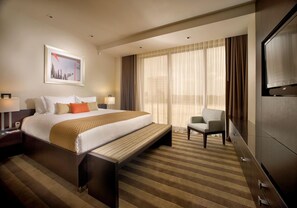 A hotel room with a large bed, a desk, a chair, a TV, and a window with curtains. - Business Suite w/ Spacious Layout| Pool Access & Free Shuttle| 5-Min to Airports (Miami Springs)