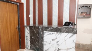A reception desk with a laptop, a wooden door, and a patterned wall.
