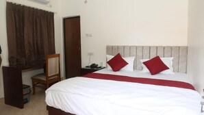 A hotel room with a bed, a desk, a chair, and a wardrobe.