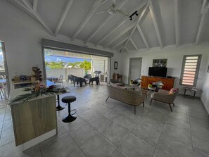 A spacious living area with a kitchen, dining area, and a large window providing a view of the outdoors. - Villa with Bungalow & Pool – Sleeps 10 (Saint-François)