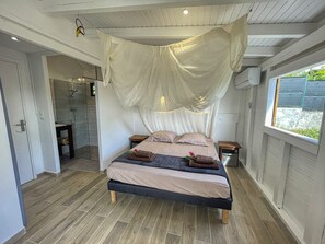 A bedroom with a bed, bedside tables, a window, and a shower area. - Villa with Bungalow & Pool – Sleeps 10 (Saint-François)