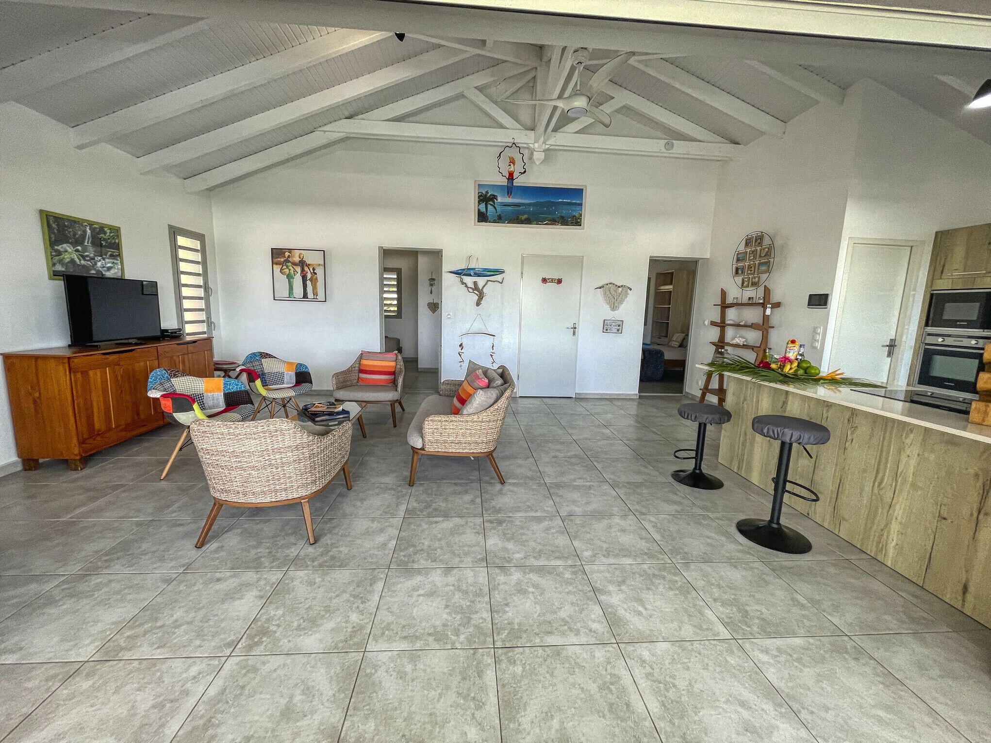 A spacious living area with high ceilings, a kitchen area with a wooden counter, and a dining area with a bar.