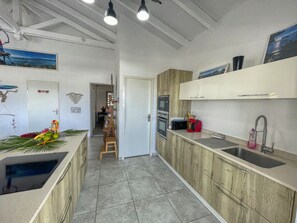 A modern kitchen with wooden cabinets, a built-in oven, and a sink. - Villa with Bungalow & Pool – Sleeps 10 (Saint-François)