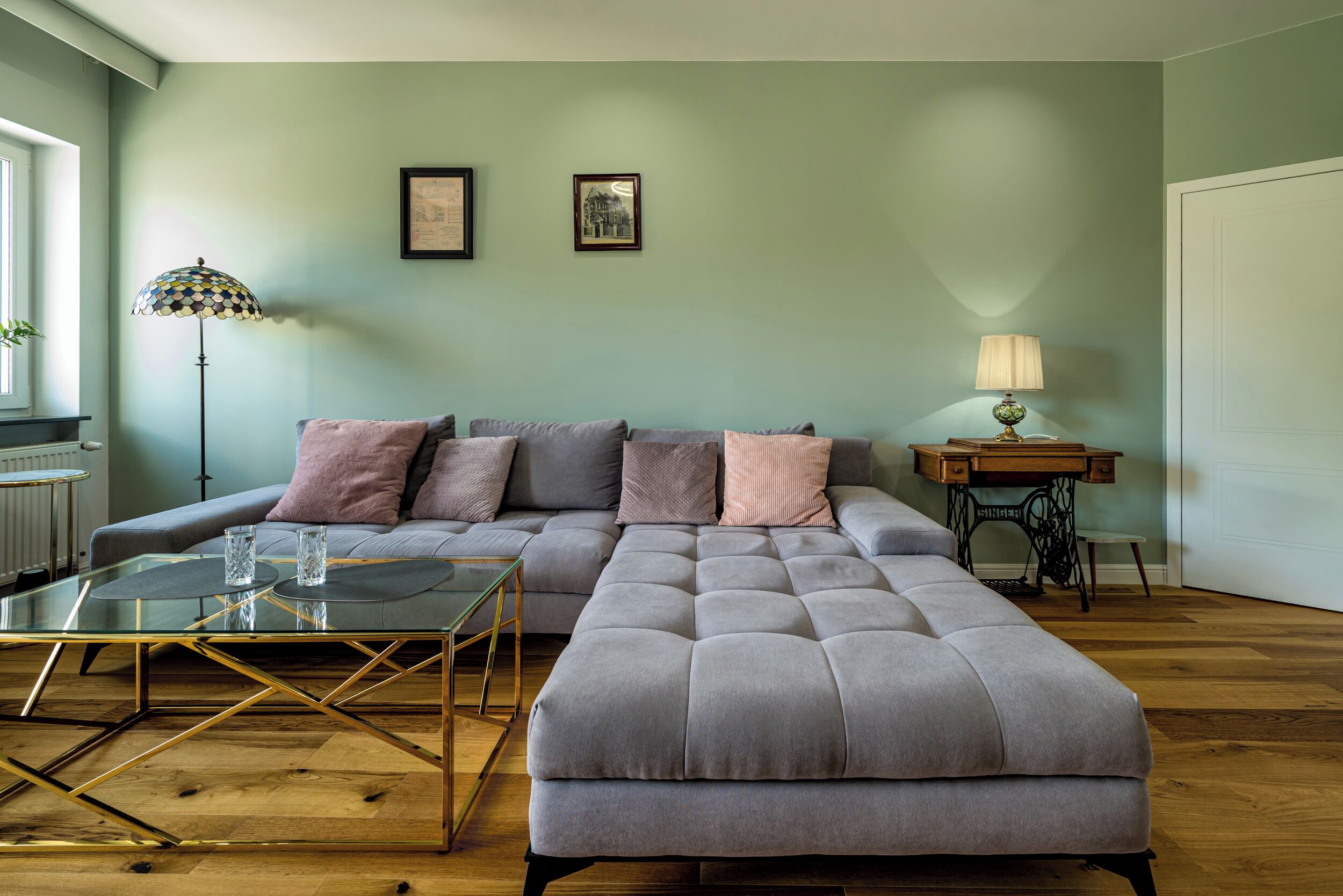A modern living room with a sectional sofa, a glass coffee table, and a vintage sewing machine.