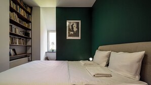 Un dormitorio con una cama grande, una estantería y un cuadro en la pared.