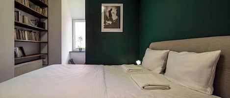 Un dormitorio con una cama grande, una estantería y un cuadro en la pared.