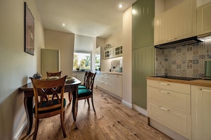 Una cocina con piso de madera, un comedor con mesa y sillas, y armarios con un mosaico decorativo.